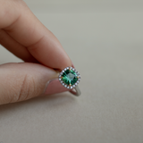Cushion cut green tourmaline set with 18ct yellow gold claws and a diamond halo in platinum. Handmade luxury in the UK and Ireland for engagement rings, wedding bands, eternity rings and classic jewellery.