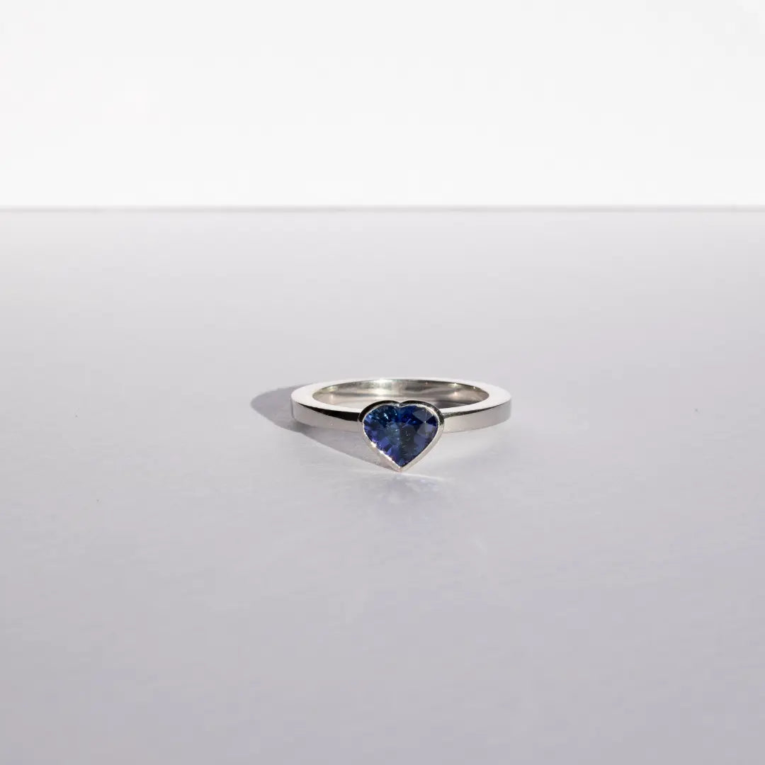 Heart shaped blue sapphire bezel set with a hidden diamond halo in platinum. Handmade luxury in the UK and Ireland for engagement rings, wedding bands, eternity rings and classic jewellery.