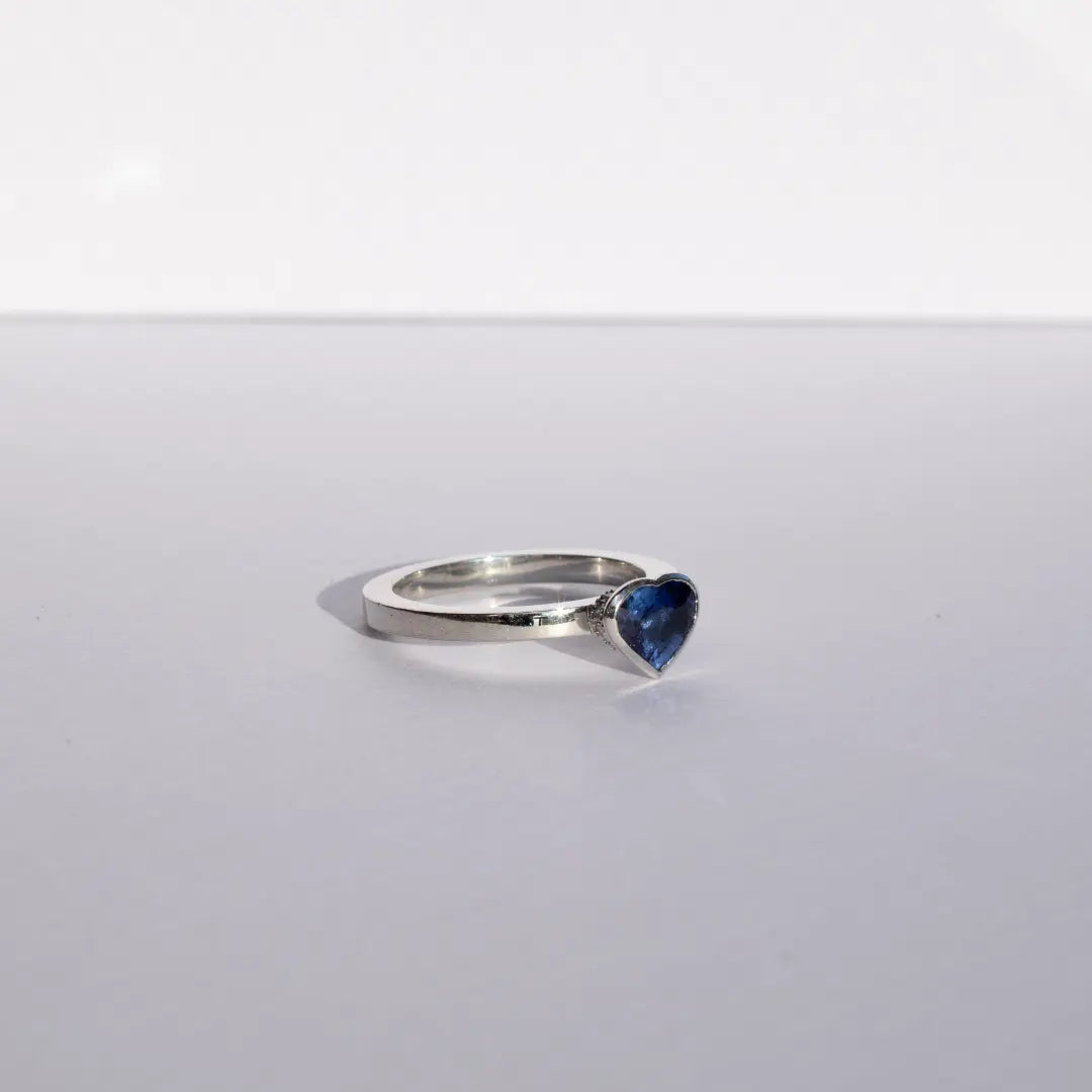Heart shaped blue sapphire bezel set with a hidden diamond halo in platinum. Handmade luxury in the UK and Ireland for engagement rings, wedding bands, eternity rings and classic jewellery.