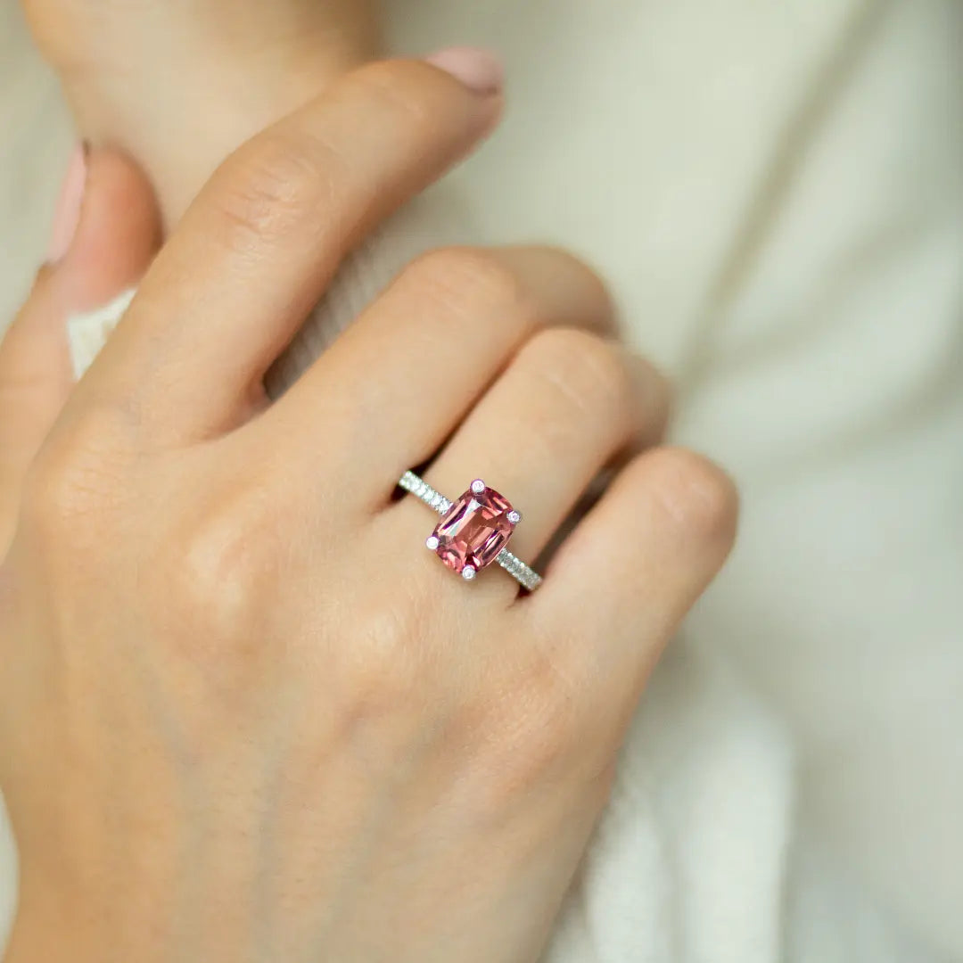 Cushion cut pink-orange tourmaline with diamond set claws, and diamond set band. Handmade luxury in the UK and Ireland for engagement rings, wedding bands, eternity rings and classic jewellery.