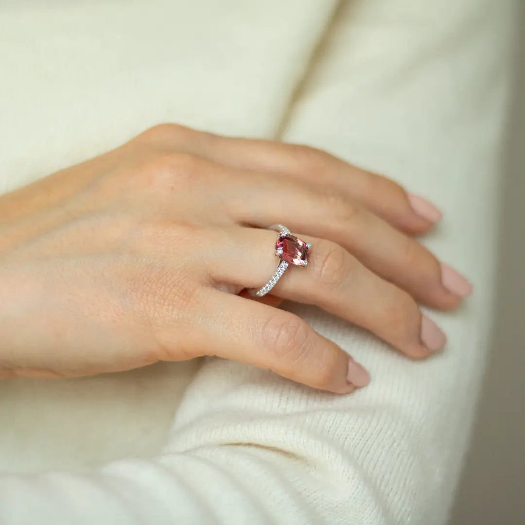 Cushion cut pink-orange tourmaline with diamond set claws, and diamond set band. Handmade luxury in the UK and Ireland for engagement rings, wedding bands, eternity rings and classic jewellery.