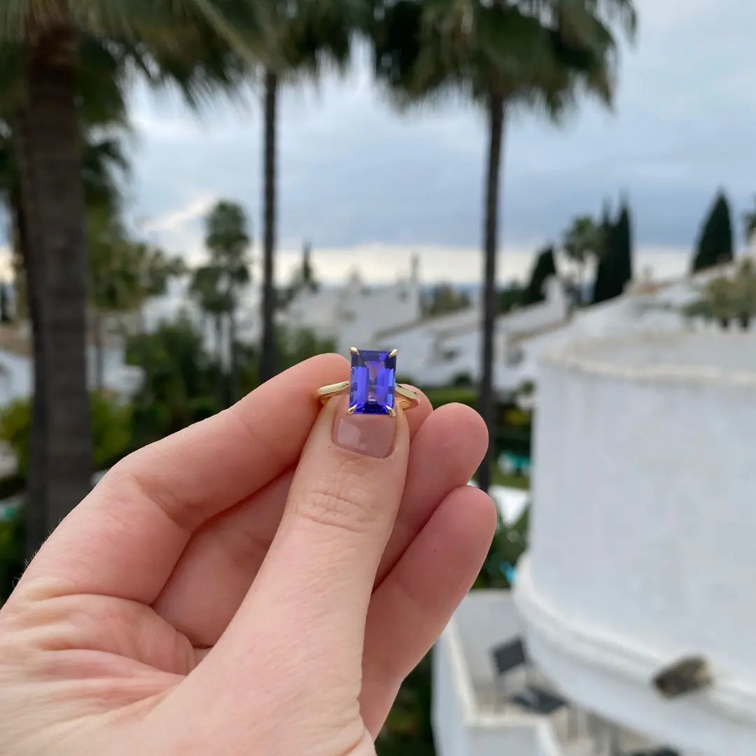 Emerald cut Tanzanite set with a talon claws in 18ct yellow gold. Handmade luxury in the UK and Ireland for engagement rings, wedding bands, eternity rings and classic jewellery.
