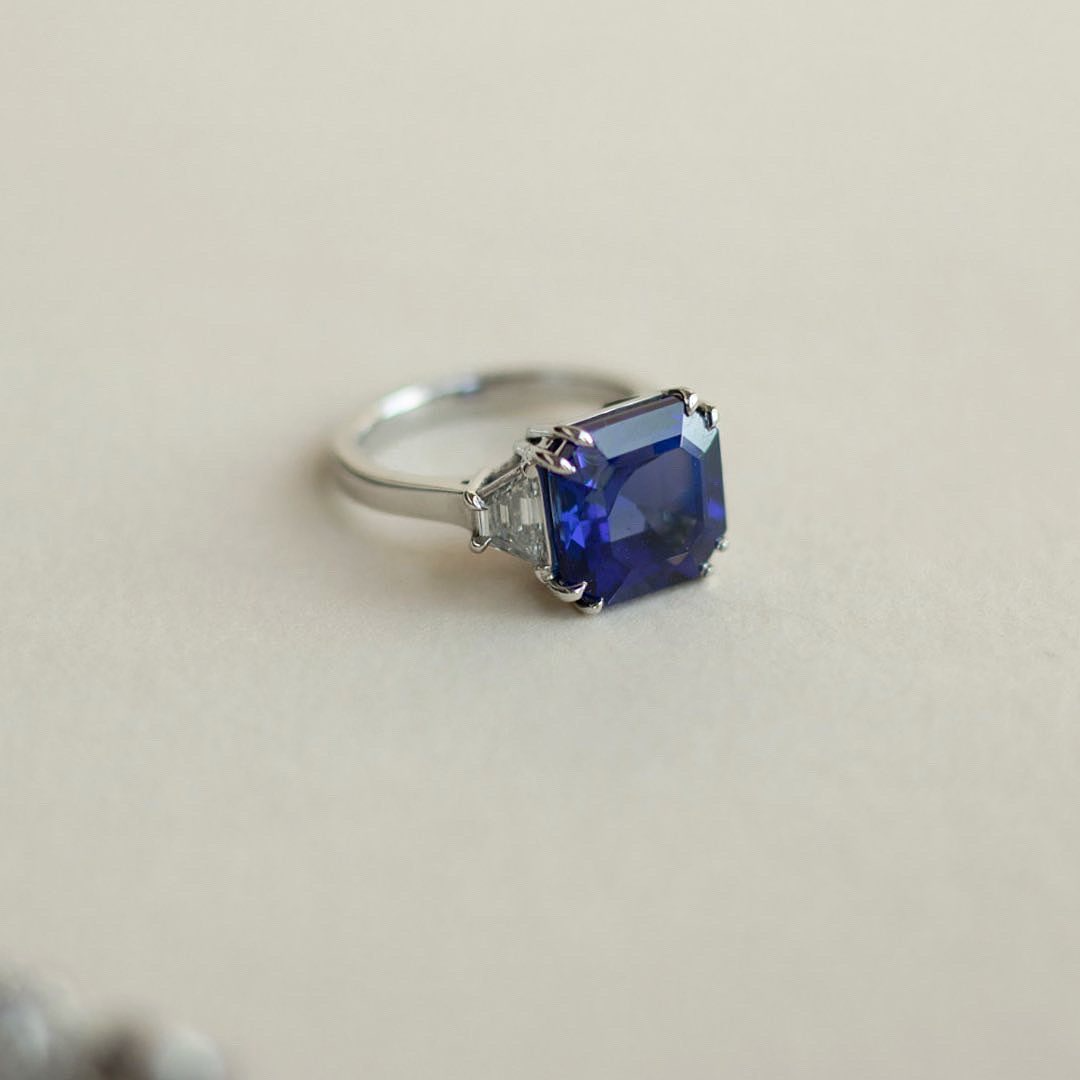 Asscher cut peacock blue tanzanite set with trapezoid cut diamond  shoulders in platinum. Handmade luxury in the UK and Ireland for engagement rings, wedding bands, eternity rings and classic jewellery.