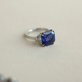 Asscher cut peacock blue tanzanite set with trapezoid cut diamond  shoulders in platinum. Handmade luxury in the UK and Ireland for engagement rings, wedding bands, eternity rings and classic jewellery.