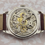 Vintage watch with visible mechanical components on a patterned background