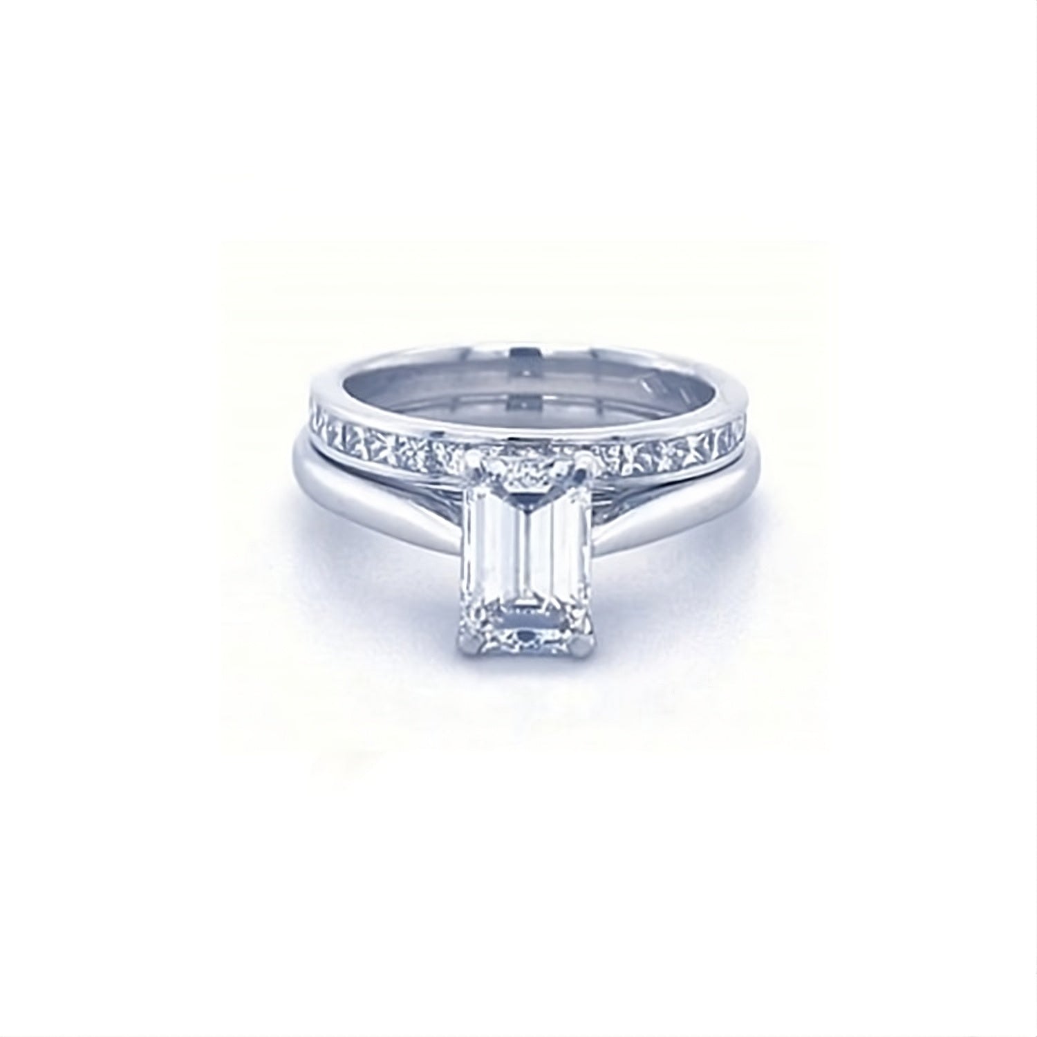 Diamond ring with emerald-cut center stone on a white background