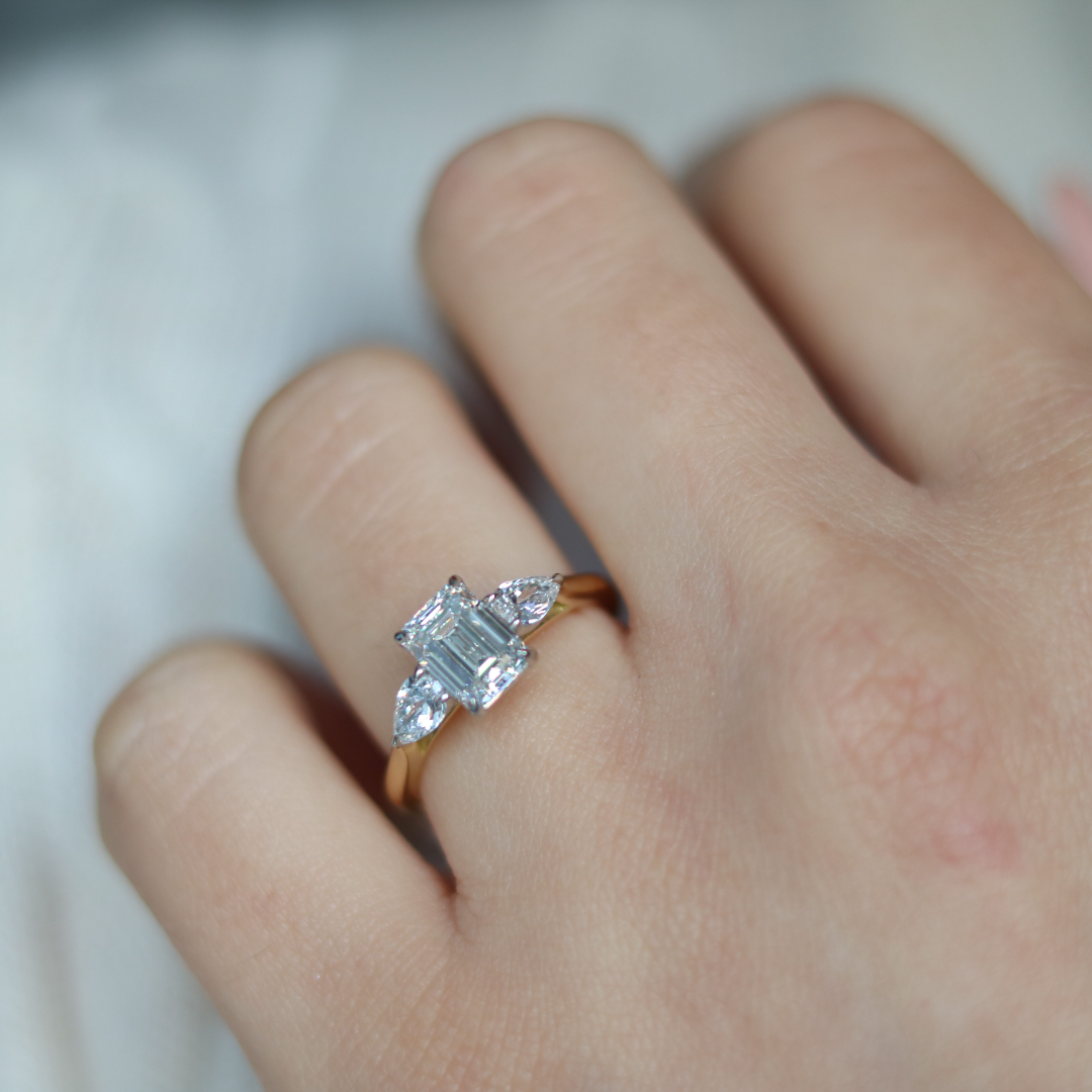 Emerald cut diamond with pear cut diamond shoulders and platinum claws and an 18ct yellow gold band. Handmade luxury in the UK and Ireland for engagement rings, wedding bands, eternity rings and classic jewellery.