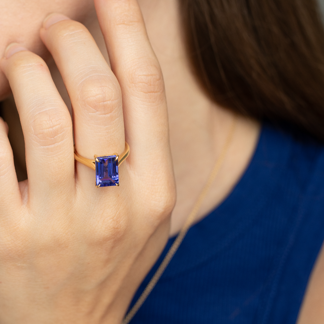 Emerald cut Tanzanite set with a talon claws in 18ct yellow gold. Handmade luxury in the UK and Ireland for engagement rings, wedding bands, eternity rings and classic jewellery.