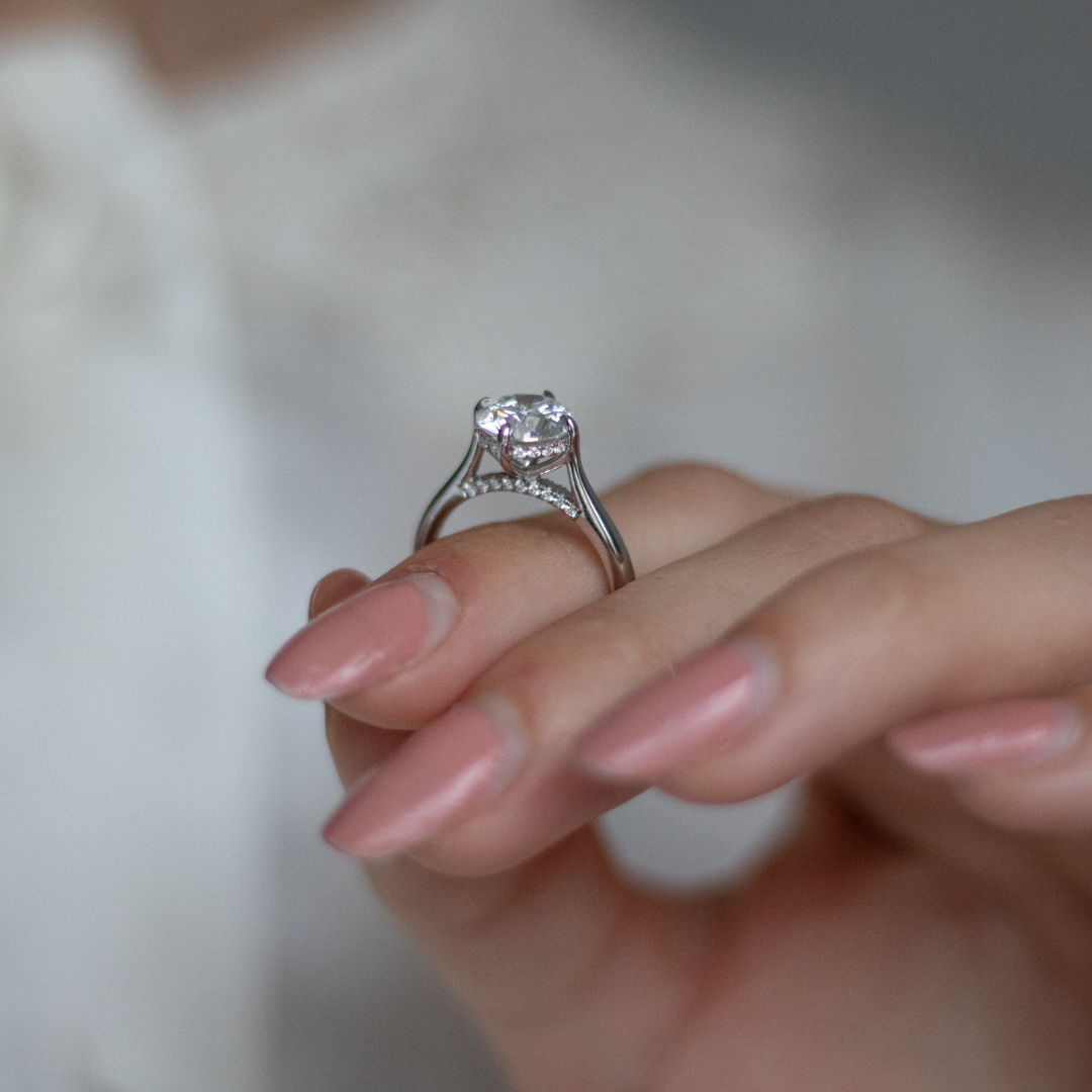 Round brilliant cut diamond with a hidden halo, platinum claws, diamond set bridge and platinum band. Handmade luxury in the UK and Ireland for engagement rings, wedding bands, eternity rings and classic jewellery.