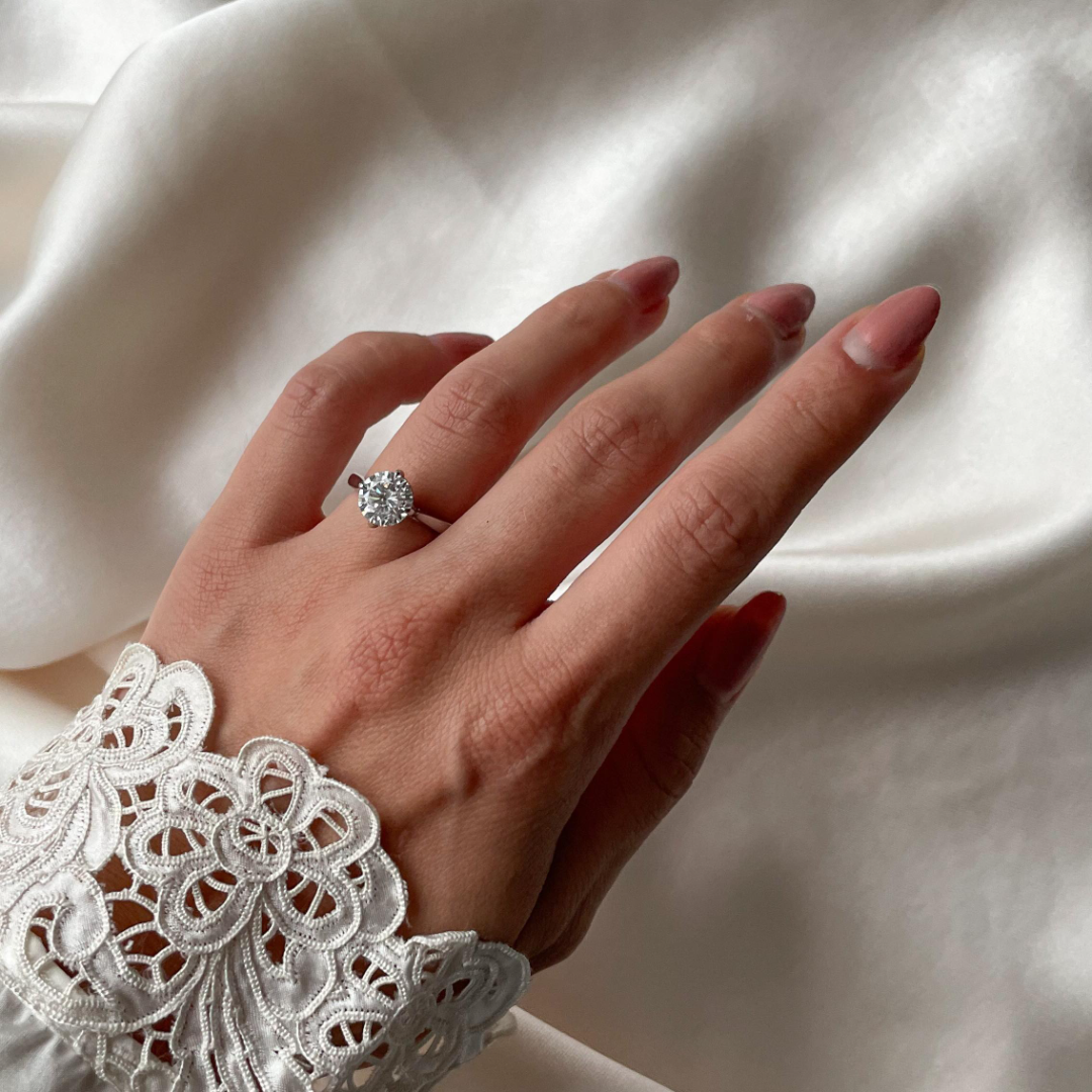 Round brilliant cut diamond with a hidden halo, platinum claws, diamond set bridge and platinum band. Handmade luxury in the UK and Ireland for engagement rings, wedding bands, eternity rings and classic jewellery.