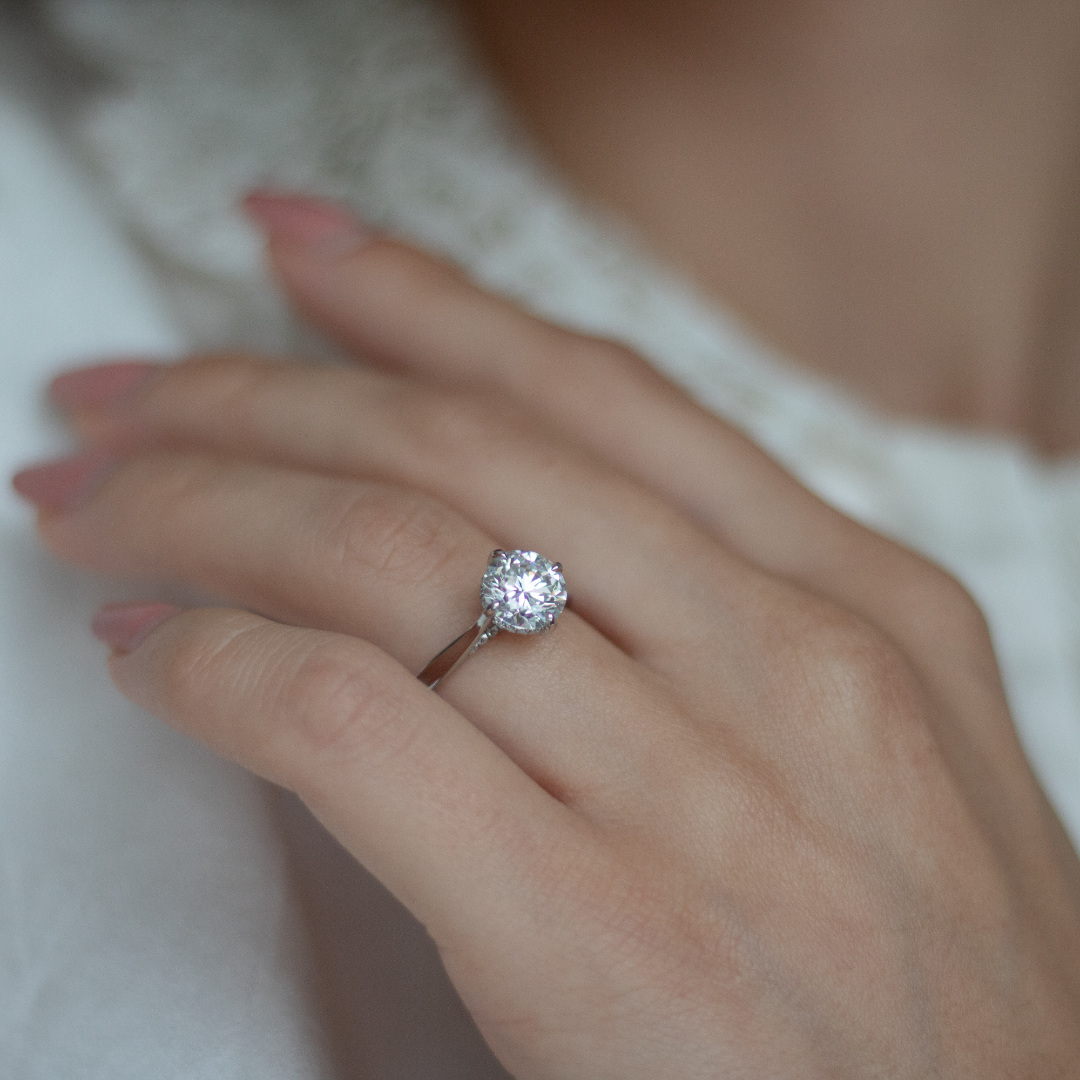 Round brilliant cut diamond with a hidden halo, platinum claws, diamond set bridge and platinum band. Handmade luxury in the UK and Ireland for engagement rings, wedding bands, eternity rings and classic jewellery.