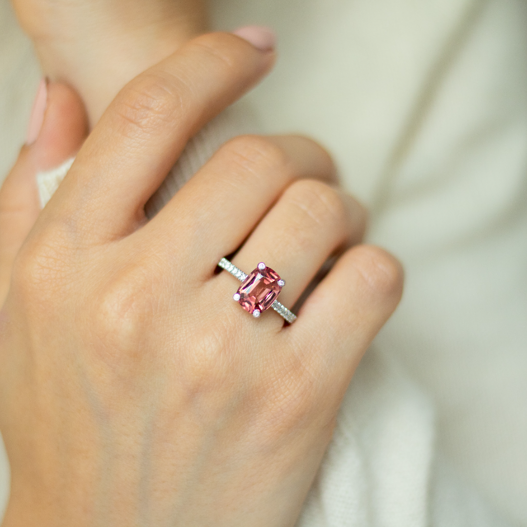Cushion cut pink-orange tourmaline with diamond set claws, and diamond set band. Handmade luxury in the UK and Ireland for engagement rings, wedding bands, eternity rings and classic jewellery.