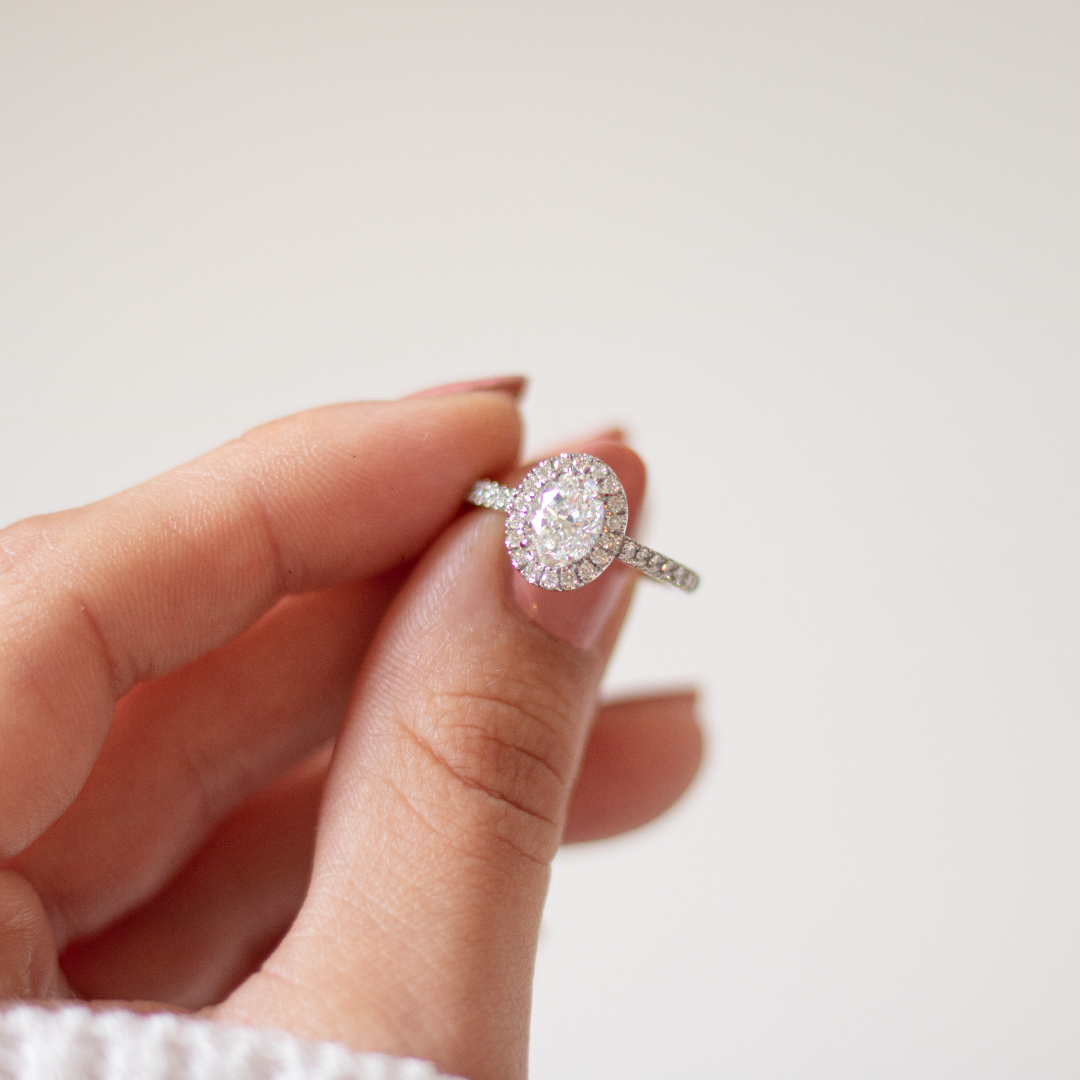 Oval cut diamond in a platinum Royal design with a halo of diamonds and diamond set band in platinum with talon claws. Handmade luxury in the UK and Ireland for engagement rings, wedding bands, eternity rings and classic jewellery.
