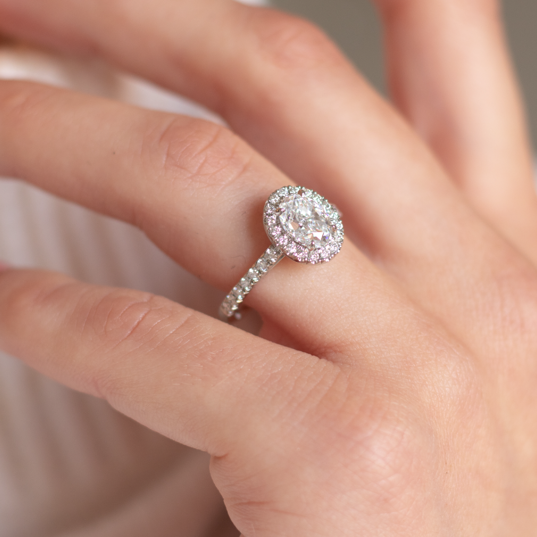 Oval cut diamond in a platinum Royal design with a halo of diamonds and diamond set band in platinum with talon claws. Handmade luxury in the UK and Ireland for engagement rings, wedding bands, eternity rings and classic jewellery.