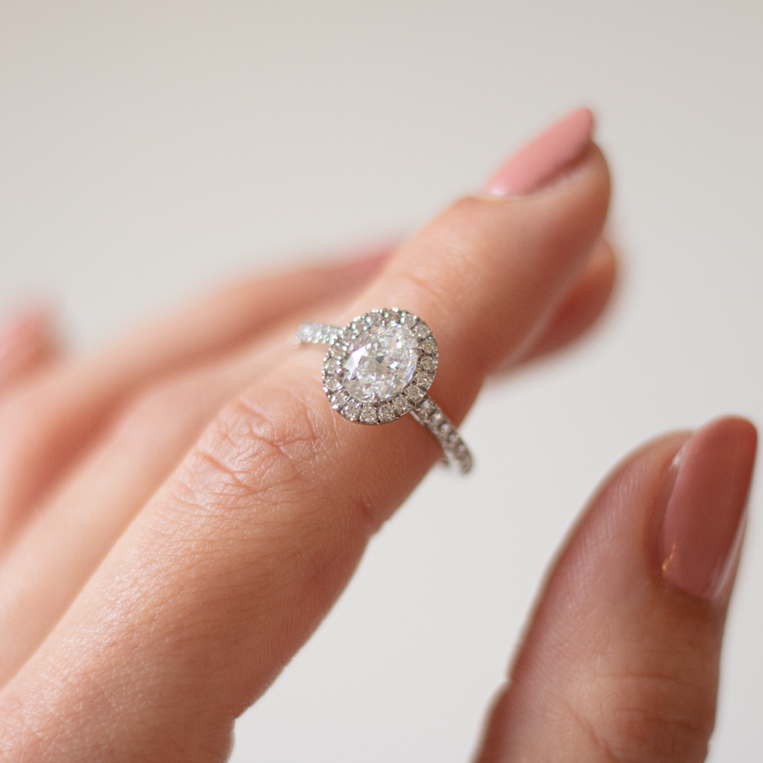 Oval cut diamond in a platinum Royal design with a halo of diamonds and diamond set band in platinum with talon claws. Handmade luxury in the UK and Ireland for engagement rings, wedding bands, eternity rings and classic jewellery.