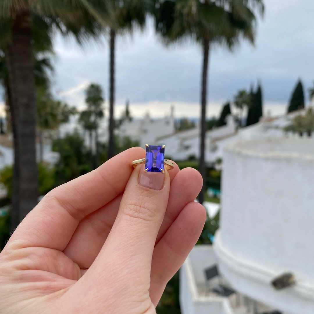 Emerald cut Tanzanite set with a talon claws in 18ct yellow gold. Handmade luxury in the UK and Ireland for engagement rings, wedding bands, eternity rings and classic jewellery.