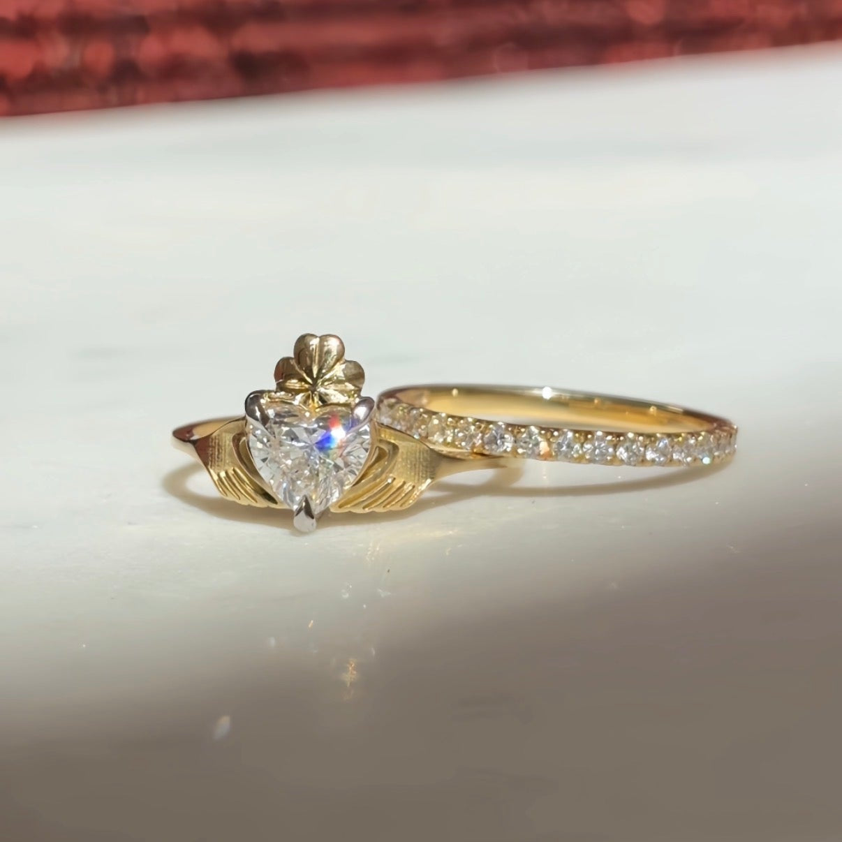 gold claddagh ring with diamond heart, sitting with a gold diamond eternity band