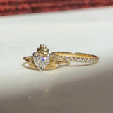 gold claddagh ring with diamond heart, sitting with a gold diamond eternity band