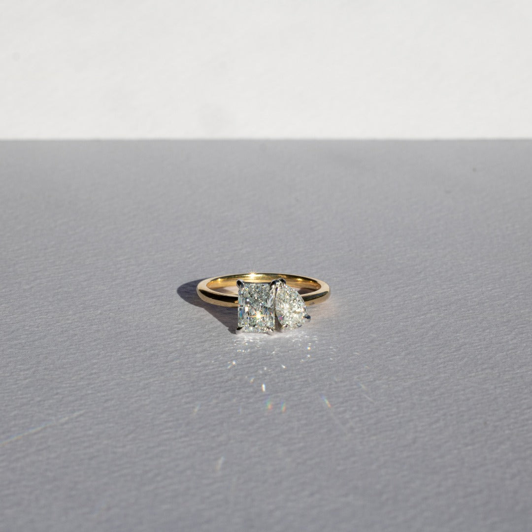Toi et Moi with radiant cut and pear cut diamonds with platinum claws on an 18ct yellow gold band. Handmade luxury in the UK and Ireland for engagement rings, wedding bands, eternity rings and classic jewellery.