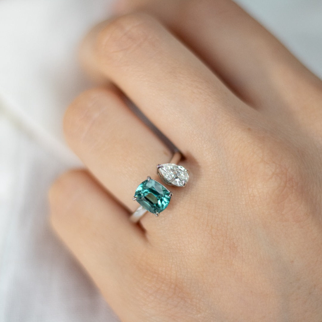 Toi et Moi with a green cushion cut tourmaline and pear cut diamond with platinum claws on a platinum band. Handmade luxury in the UK and Ireland for engagement rings, wedding bands, eternity rings and classic jewellery.