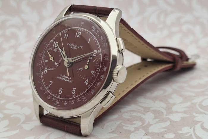Vintage wristwatch with wine strap and detailed face on a light background