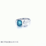 Toi et Moi with a green cushion cut tourmaline and pear cut diamond with platinum claws on a platinum band. Handmade luxury in the UK and Ireland for engagement rings, wedding bands, eternity rings and classic jewellery.